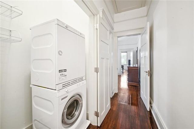 laundry area featuring dark wood-type flooring and stacked washer / dryer