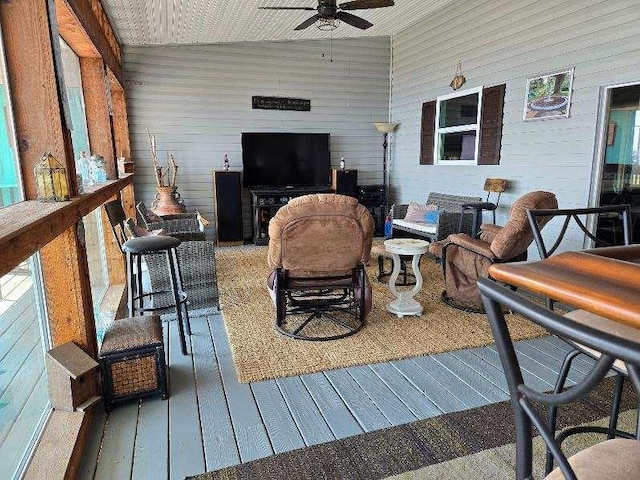 living room featuring ceiling fan, hardwood / wood-style flooring, and wooden walls