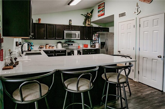 kitchen with kitchen peninsula, a kitchen breakfast bar, dark hardwood / wood-style floors, sink, and stainless steel appliances