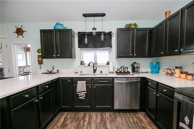 kitchen featuring appliances with stainless steel finishes, sink, kitchen peninsula, hanging light fixtures, and dark wood-type flooring