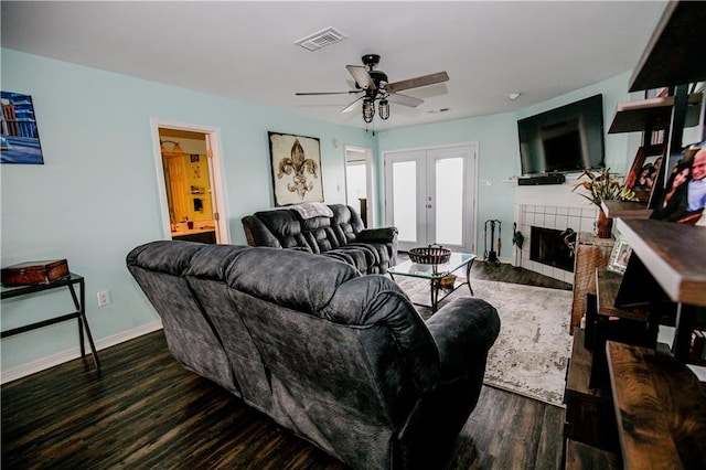 living room with french doors, a tiled fireplace, ceiling fan, and dark hardwood / wood-style flooring