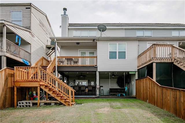 rear view of property featuring a deck and a lawn