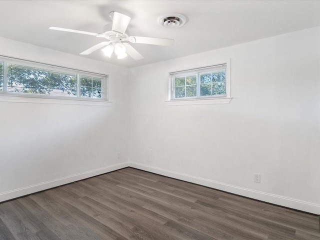 empty room featuring ceiling fan, dark wood-type flooring, and a healthy amount of sunlight