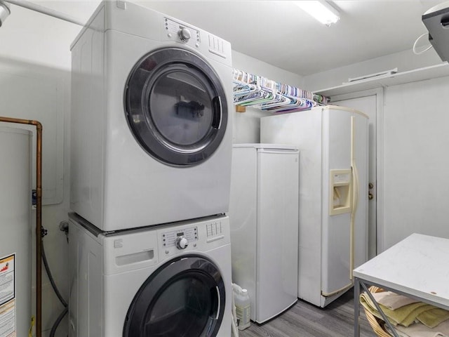 washroom featuring hardwood / wood-style floors, gas water heater, and stacked washer and dryer