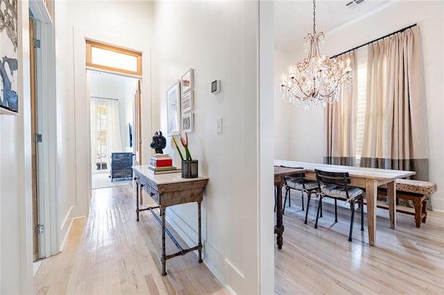 hallway featuring an inviting chandelier and light hardwood / wood-style flooring