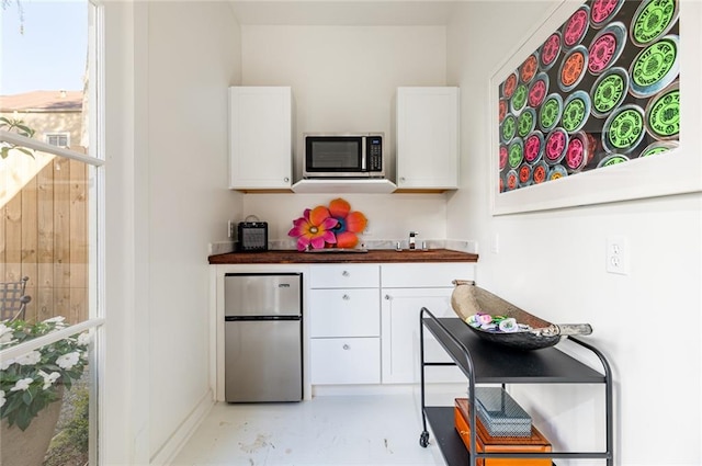 kitchen with wooden counters, stainless steel appliances, and white cabinets