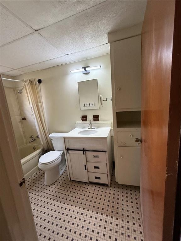 full bathroom featuring a drop ceiling, vanity, shower / tub combo, and toilet