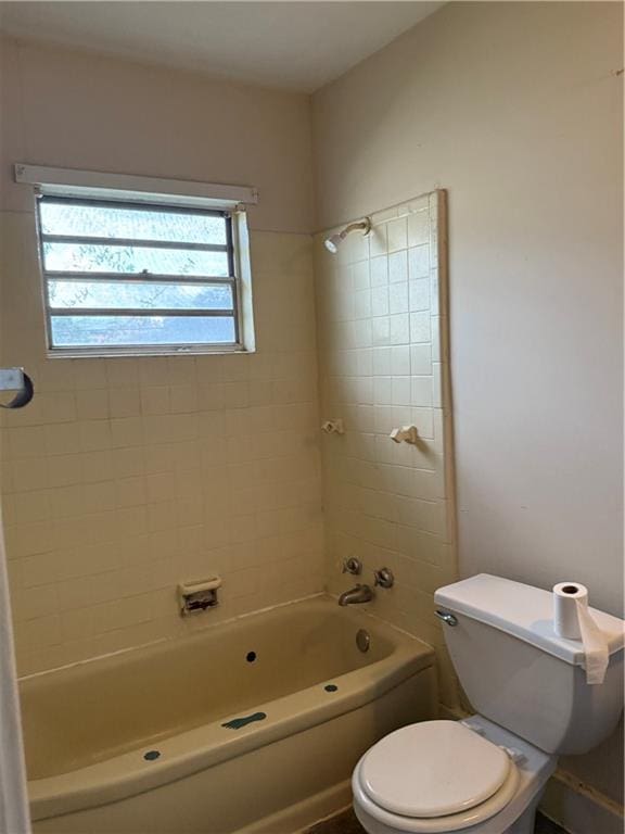 bathroom featuring tiled shower / bath combo and toilet