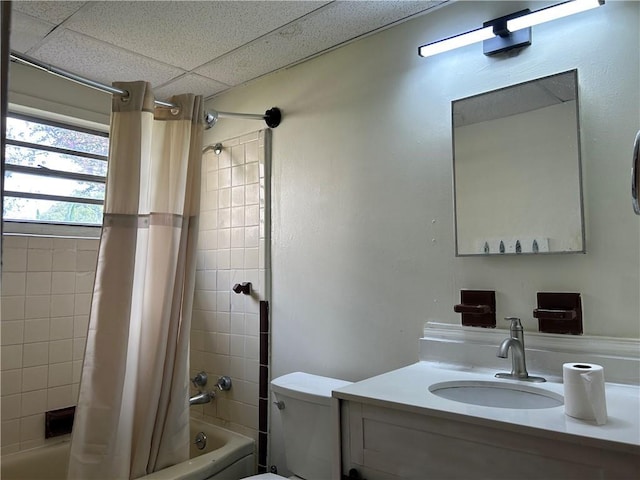 full bathroom with a paneled ceiling, shower / bath combo with shower curtain, vanity, and toilet