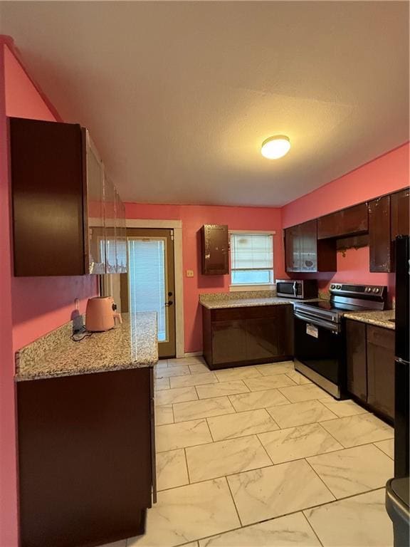 kitchen with light stone countertops, appliances with stainless steel finishes, dark brown cabinetry, and decorative light fixtures