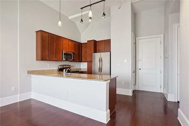 kitchen with appliances with stainless steel finishes, kitchen peninsula, high vaulted ceiling, and hanging light fixtures