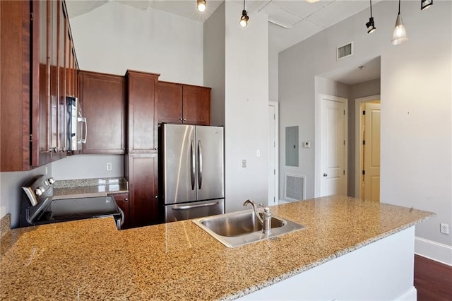 kitchen with stainless steel appliances, pendant lighting, a high ceiling, and sink