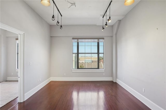 spare room featuring dark wood-type flooring and rail lighting