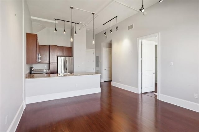 kitchen with high vaulted ceiling, dark hardwood / wood-style floors, stainless steel appliances, pendant lighting, and track lighting