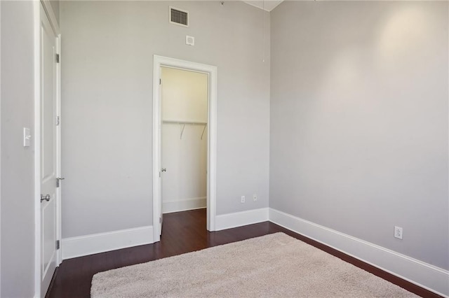 unfurnished bedroom with a closet, dark hardwood / wood-style floors, and a walk in closet