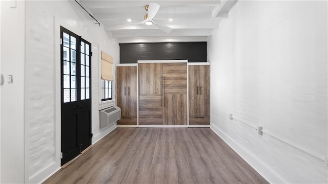 foyer featuring beam ceiling, hardwood / wood-style flooring, a wall unit AC, and ceiling fan