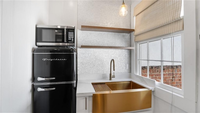 kitchen featuring pendant lighting, sink, refrigerator, and white cabinets