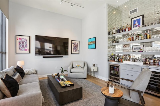 living room featuring a high ceiling, beverage cooler, indoor bar, and wood-type flooring