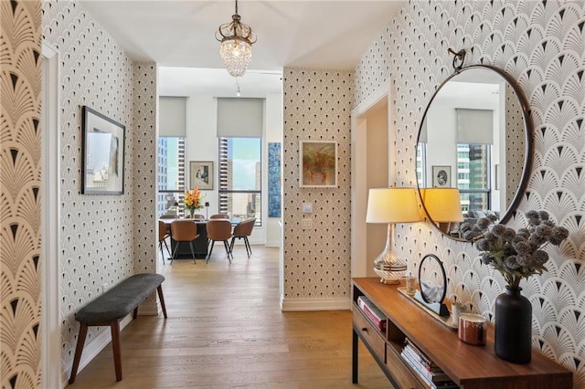 hall with hardwood / wood-style floors and an inviting chandelier