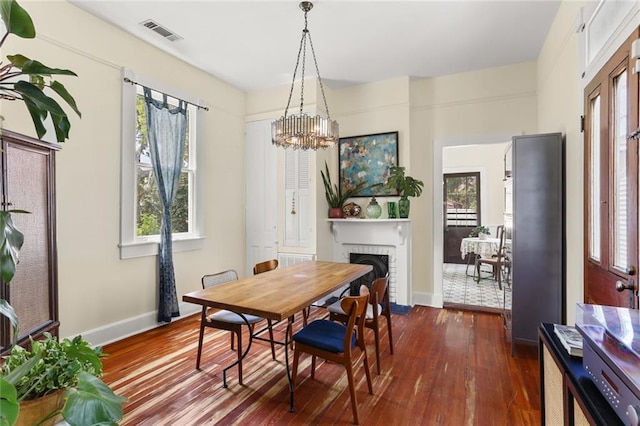 dining area featuring a fireplace, an inviting chandelier, dark hardwood / wood-style flooring, and a wealth of natural light