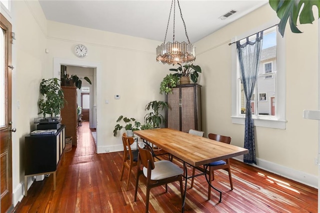 dining area with dark wood-type flooring and a notable chandelier