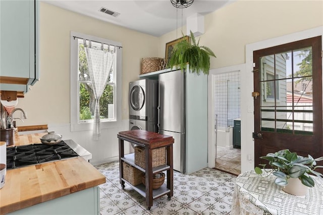 kitchen featuring stacked washing maching and dryer, stainless steel fridge, and sink