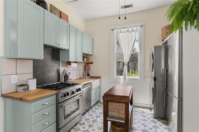 kitchen featuring decorative backsplash, appliances with stainless steel finishes, sink, and wood counters