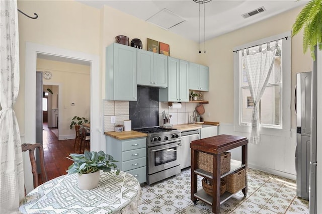 kitchen featuring butcher block counters, a healthy amount of sunlight, stainless steel appliances, and light wood-type flooring