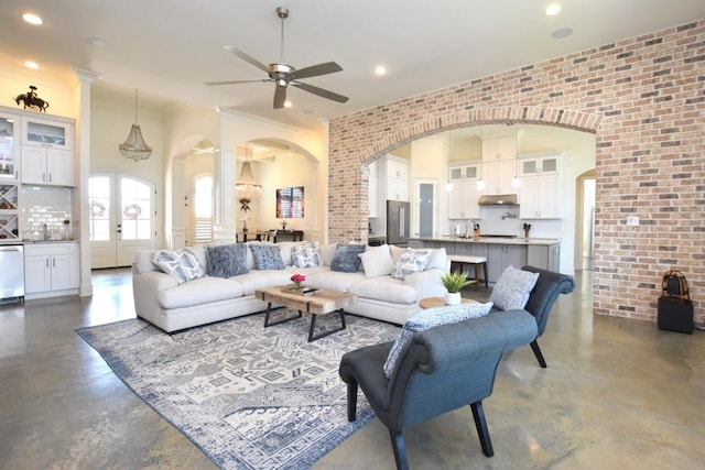 living room with crown molding, ceiling fan, and brick wall