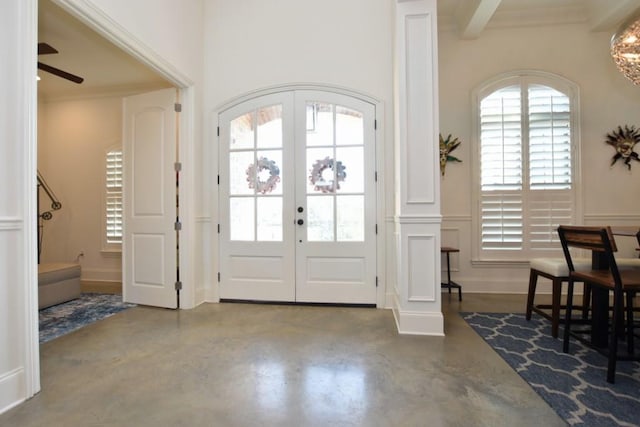 foyer featuring ornamental molding, french doors, ceiling fan, and concrete floors