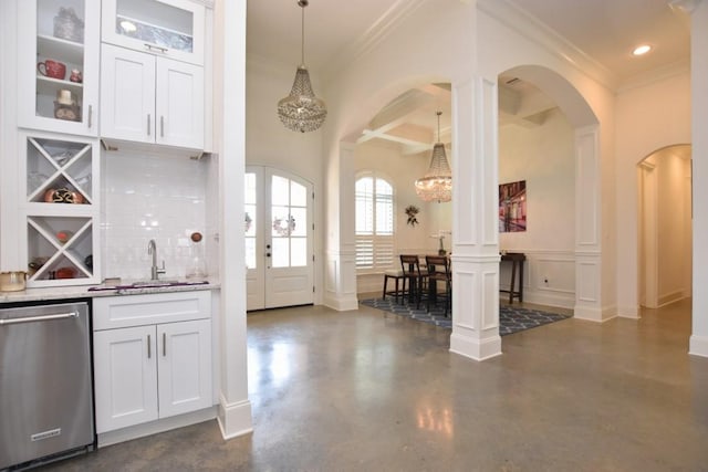 kitchen featuring tasteful backsplash, hanging light fixtures, white cabinets, dishwasher, and a chandelier