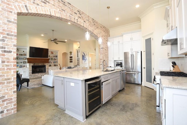 kitchen featuring high end fridge, beverage cooler, concrete floors, a kitchen island with sink, and pendant lighting