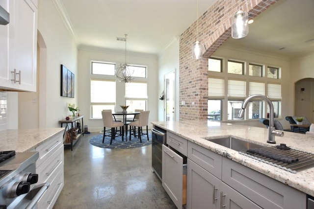 kitchen featuring pendant lighting, a wealth of natural light, light stone counters, and white cabinets