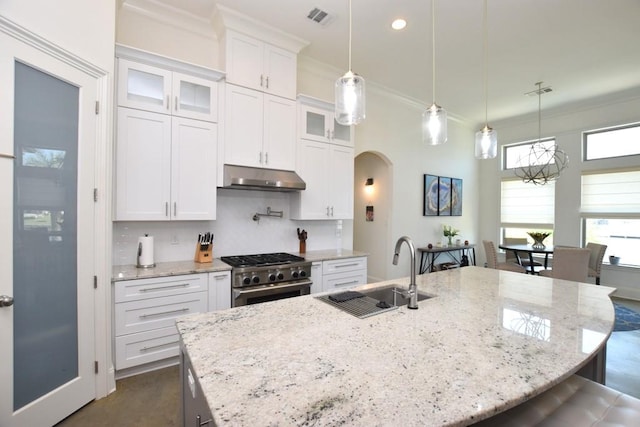 kitchen with a center island with sink, sink, high end range, and white cabinets