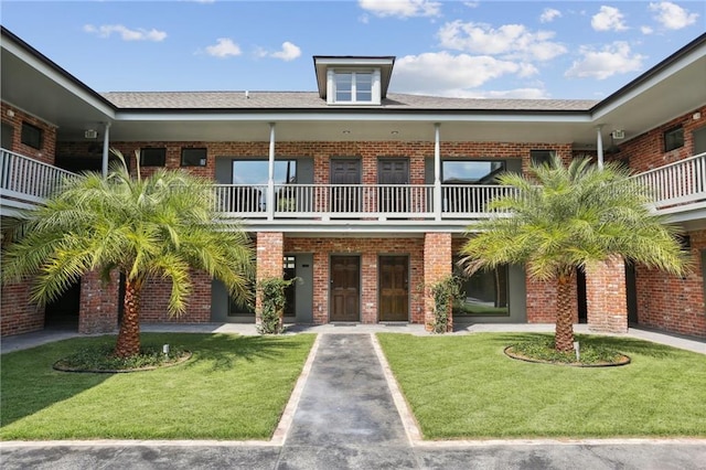 view of front of property featuring a balcony and a front lawn