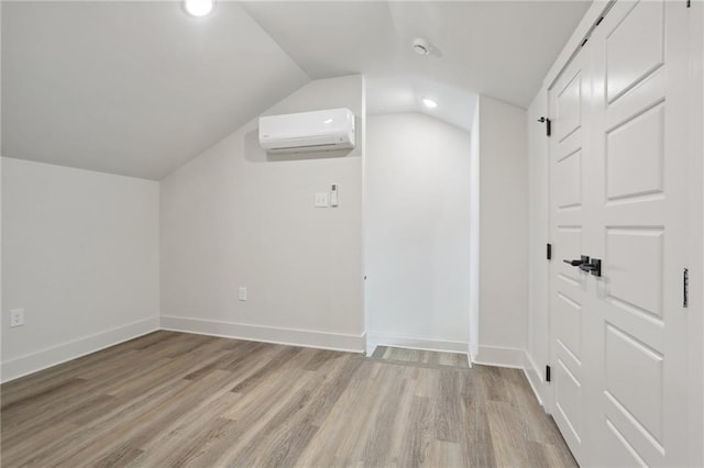 additional living space with lofted ceiling, light wood-type flooring, and a wall mounted air conditioner