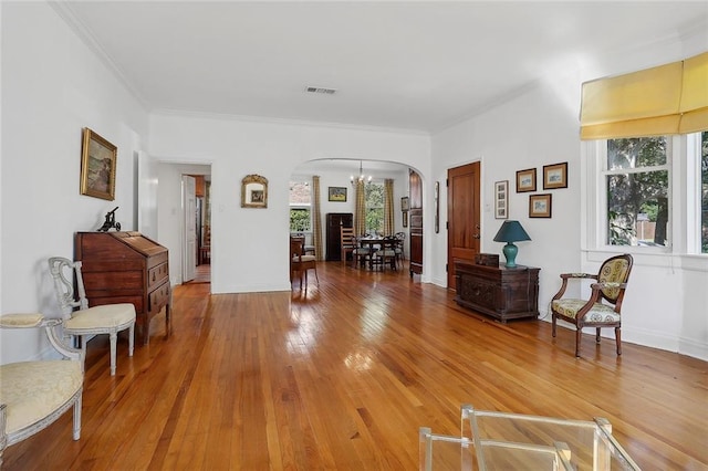 living area featuring wood-type flooring, a chandelier, and ornamental molding