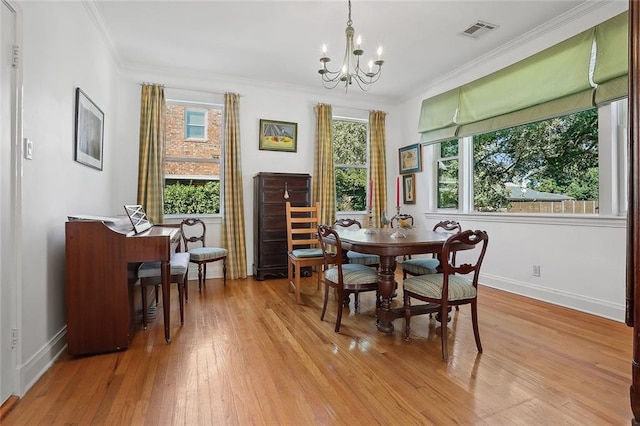 dining area with plenty of natural light, light hardwood / wood-style floors, crown molding, and a chandelier