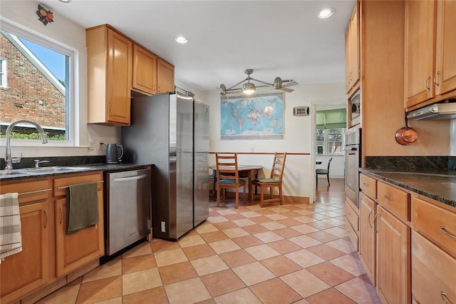 kitchen featuring ceiling fan, light tile patterned floors, sink, stainless steel appliances, and dark stone countertops