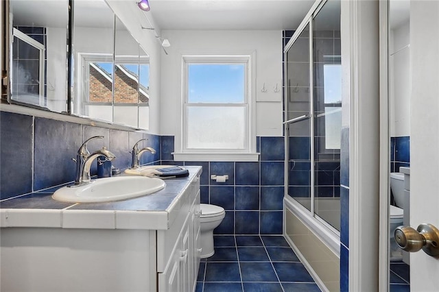 full bathroom with vanity, enclosed tub / shower combo, tile walls, tile patterned flooring, and toilet