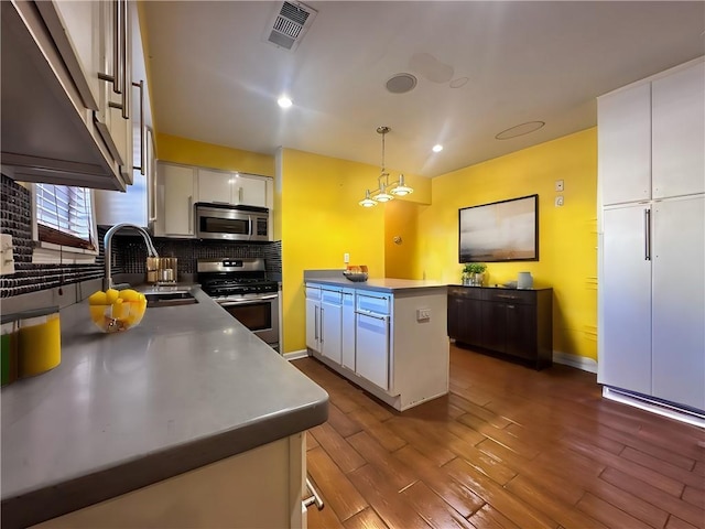 kitchen featuring pendant lighting, a kitchen island, white cabinetry, appliances with stainless steel finishes, and dark hardwood / wood-style floors