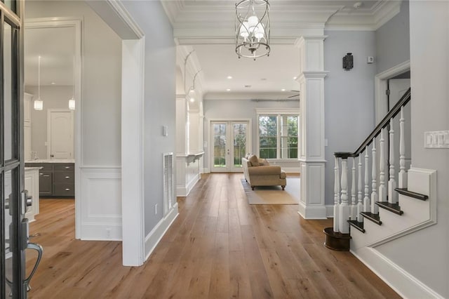 entryway featuring french doors, an inviting chandelier, light wood-type flooring, and crown molding