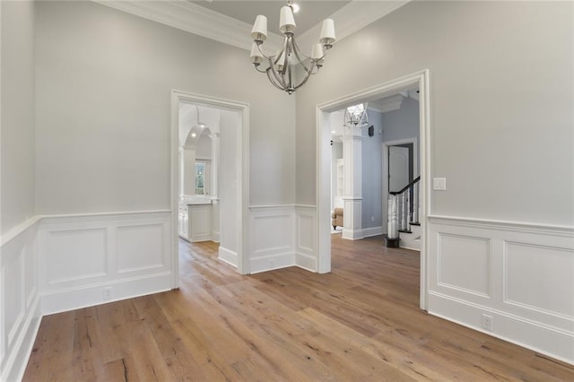 unfurnished dining area with ornamental molding, hardwood / wood-style flooring, and an inviting chandelier