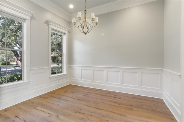 unfurnished room with hardwood / wood-style floors, plenty of natural light, ornamental molding, and a chandelier