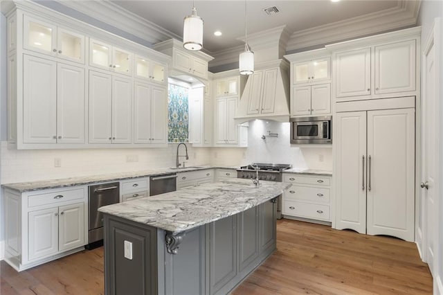 kitchen with light hardwood / wood-style floors, built in appliances, a kitchen bar, a center island, and white cabinetry