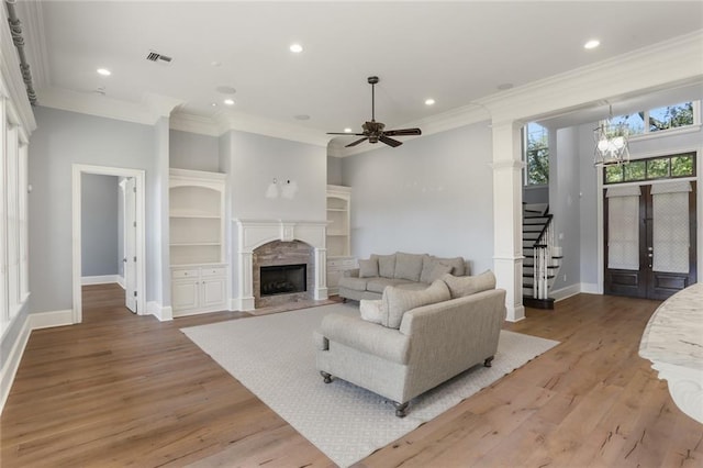 living room with ceiling fan with notable chandelier, hardwood / wood-style flooring, and crown molding