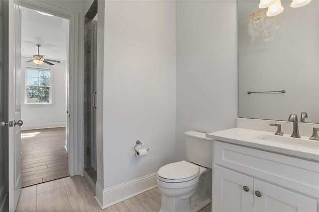 bathroom featuring wood-type flooring, vanity, ceiling fan with notable chandelier, and toilet