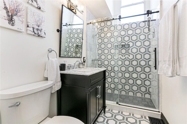 bathroom featuring a tile shower, vanity, and toilet