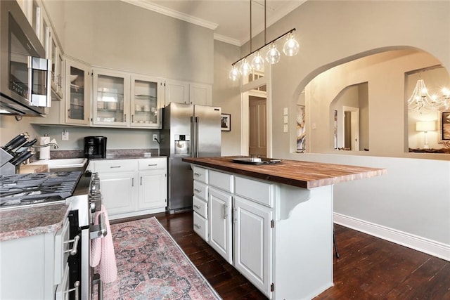 kitchen featuring wooden counters, appliances with stainless steel finishes, white cabinetry, and a kitchen island