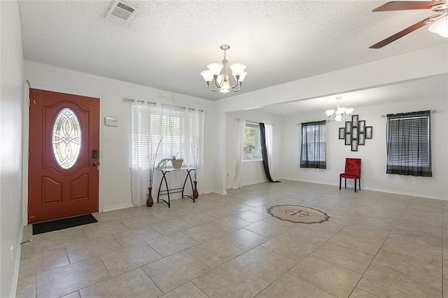 tiled foyer with a textured ceiling and ceiling fan with notable chandelier